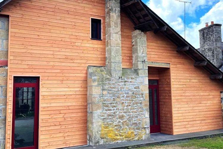 photo du bardage bois en Douglass avec les menuiseries rouge  et du conduit de cheminée en pierre